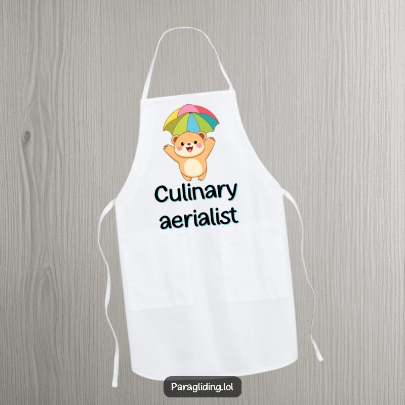 Funny apron showing a joyful, round bear cub paragliding with a colorful canopy, ideal for kitchen use or BBQs with a sense of adventure.