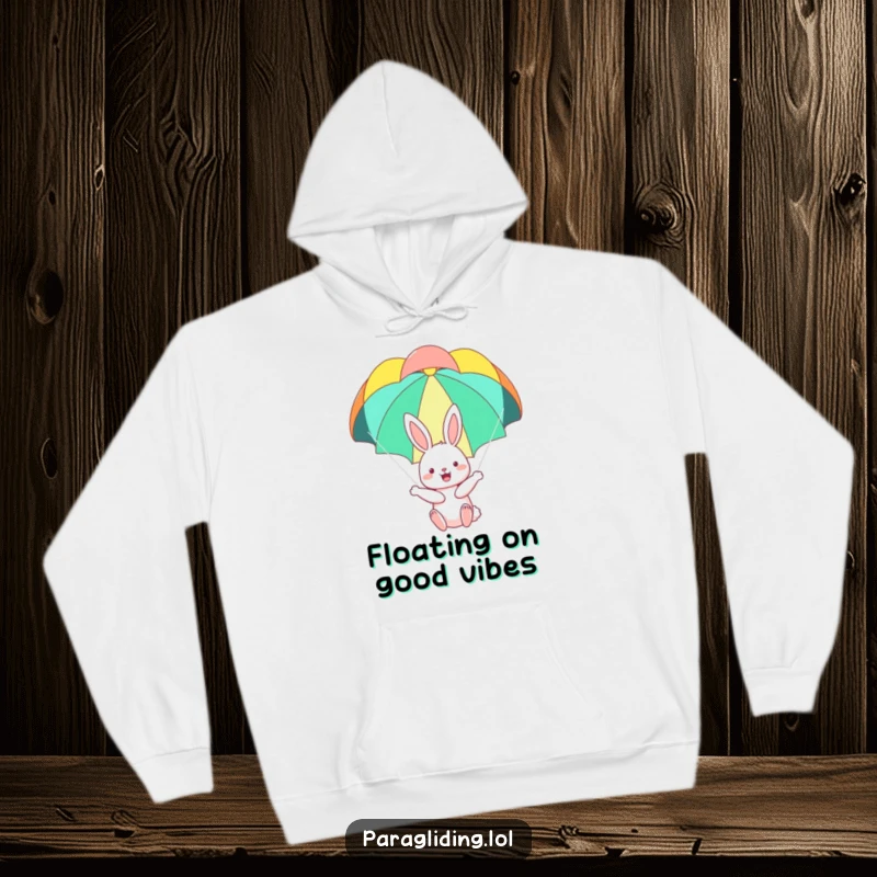 Funny hoodie depicting a happy bunny floating peacefully under a colorful parachute, perfect for staying warm with a sense of whimsical adventure.