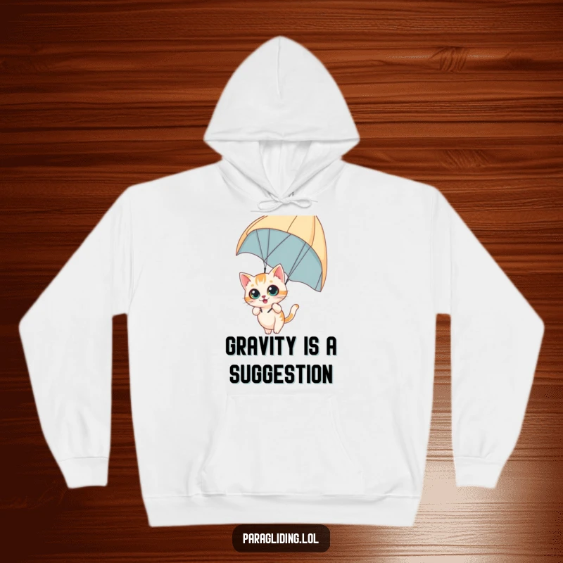 Funny hoodie depicting a curious cat dangling from a paraglider with wide eyes, offering cozy comfort and adventurous spirit, ideal funny gift.