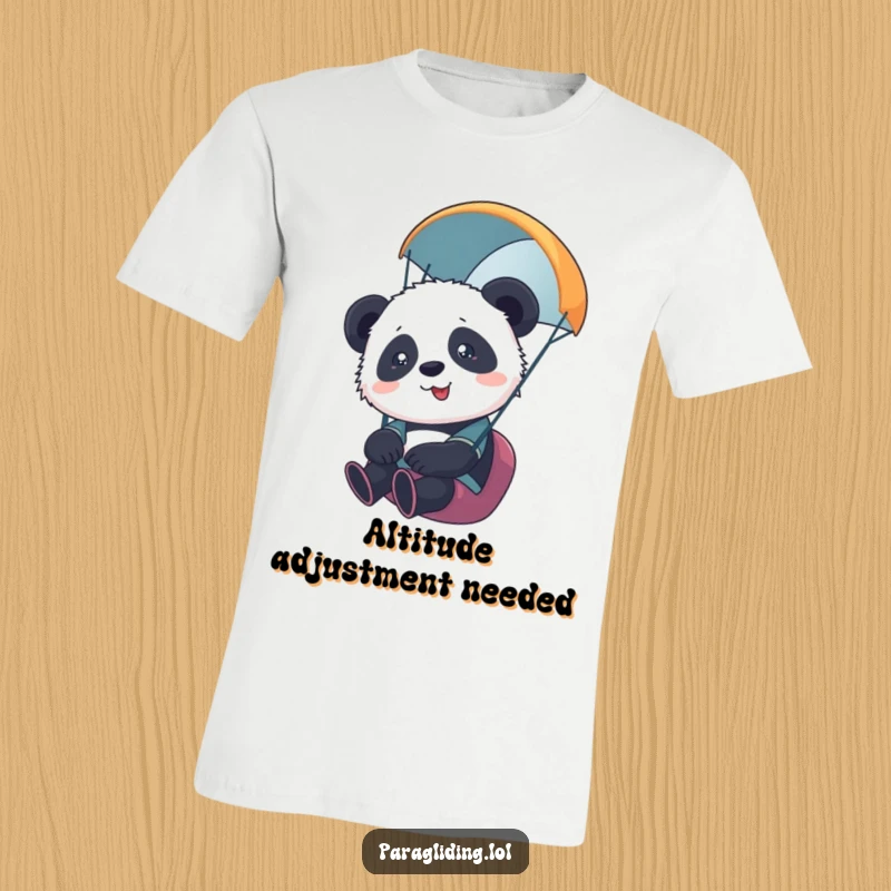 Funny t-shirt featuring a cute, slightly scared panda cub paragliding, looking overwhelmed by the amazing view and height.