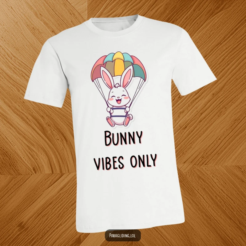 Funny t-shirt graphic of a smiling bunny paragliding under a colorful chute, perfect for adventure enthusiasts.