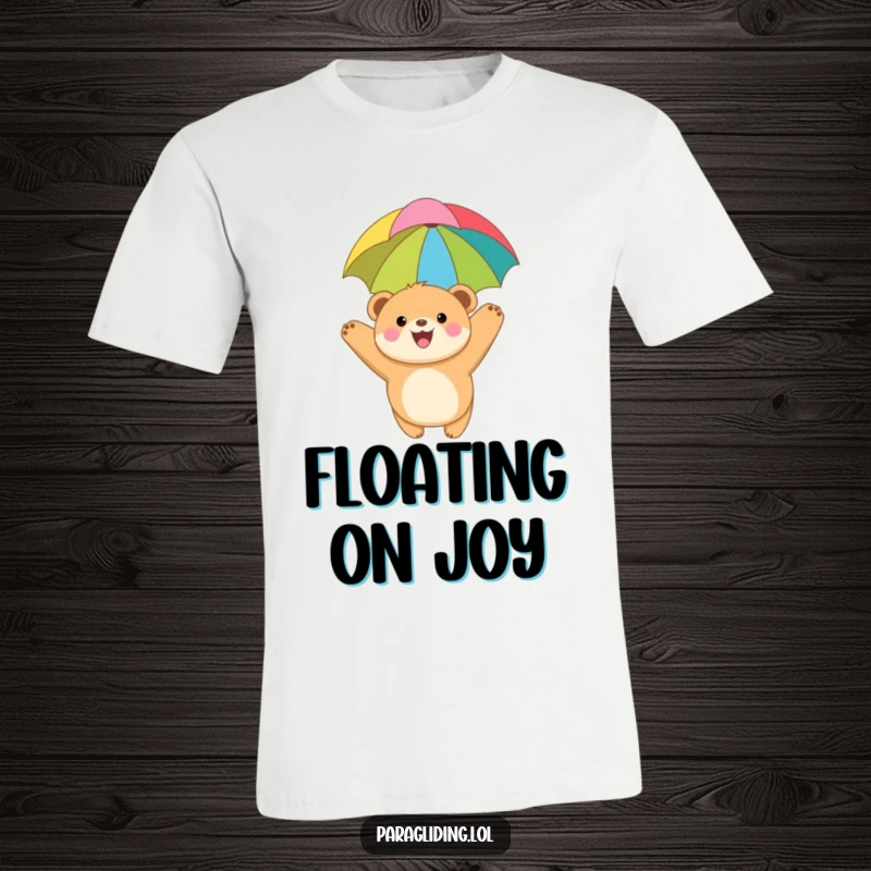 Funny t-shirt depicting a joyful, round bear cub soaring through the air with a bright, colorful paragliding canopy, embodying pure exhilaration.