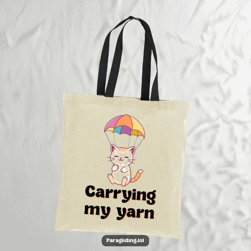 Funny tote bag with a happy cat serenely paragliding under a colorful paraglider, perfect for carrying essentials.